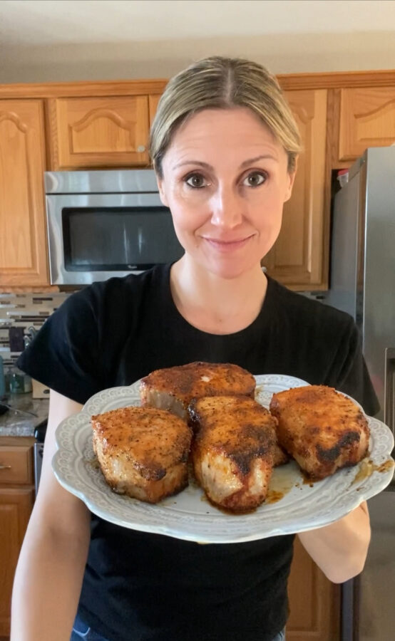 woman holding plate of air fried pork chops