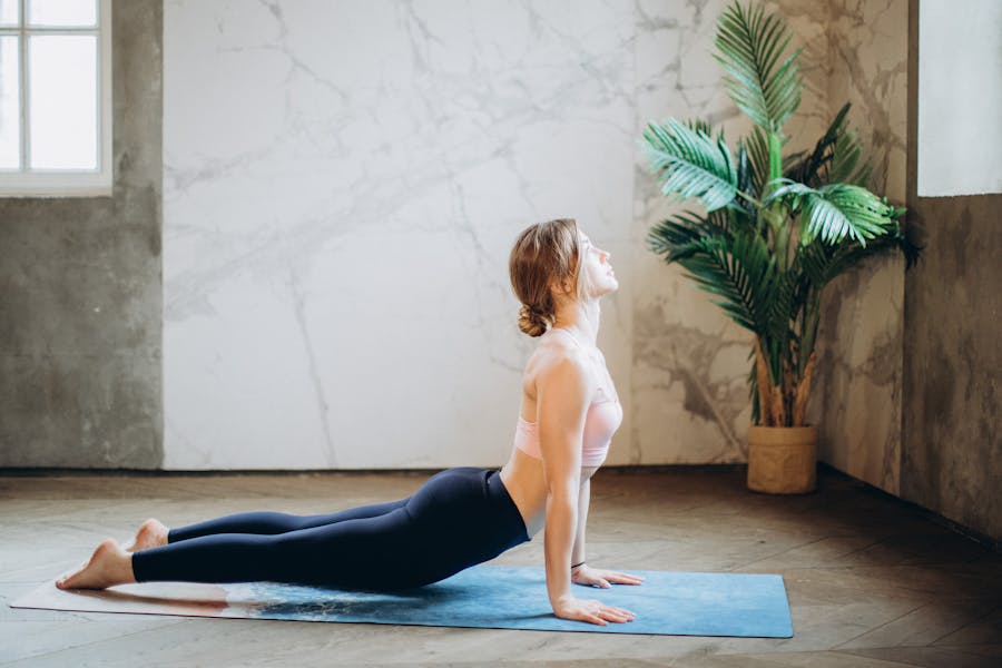 Woman in Pink Sports Bra and Black Leggings Doing Yoga on Yoga Mat