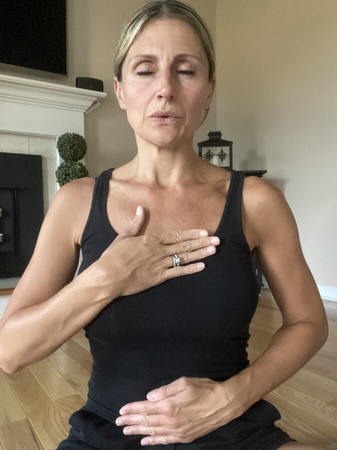 woman breathing with hand over heart and hand on abdomen