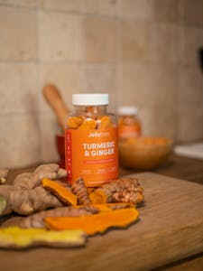 Orange Plastic Bottle on Brown Wooden Table with ginger and turmeric root
