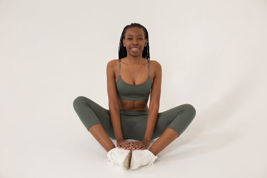 Full length of young African American female practicing yoga and sitting in Butterfly posture on floor and smiling