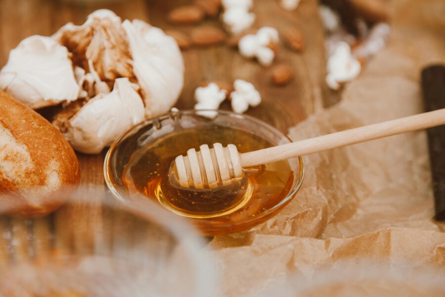 a bowl of honey in a bowl with garlic cloves behind the bowl